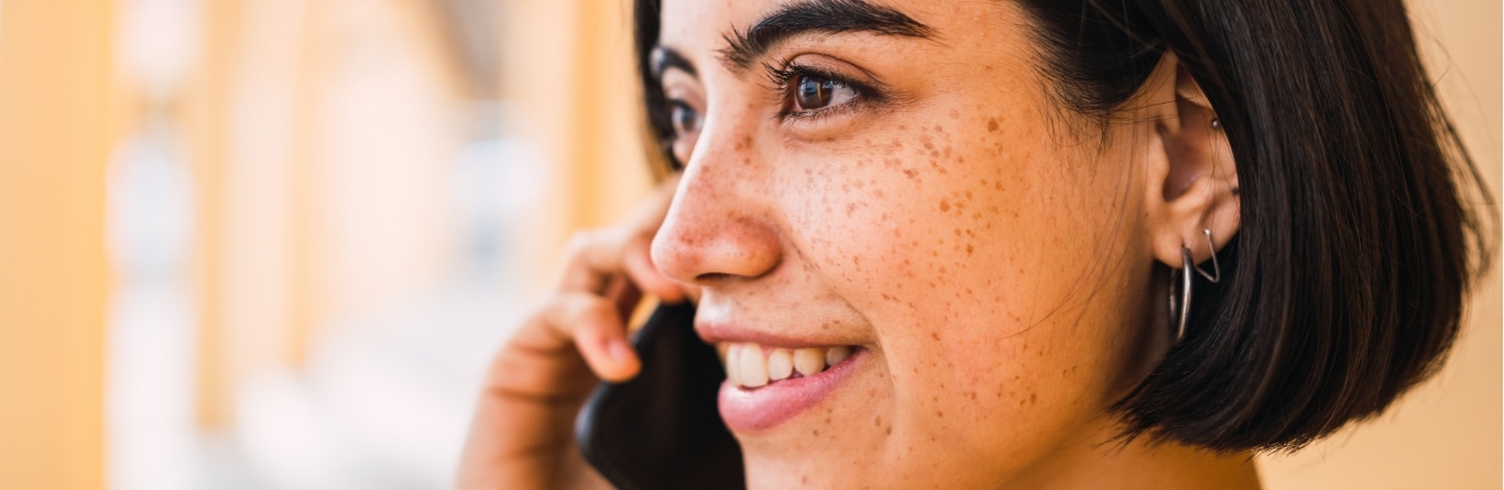 Mujer joven sonriente hablando por teléfono móvil